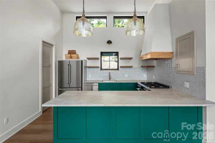 Beautiful, efficient kitchen with large THOR gas stove, champagne quartzite countertops, and a custom hoodvent.