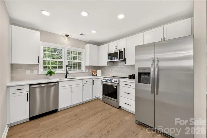 Kitchen with new cabinetry, appliances, backsplash, lighting, and fixtures