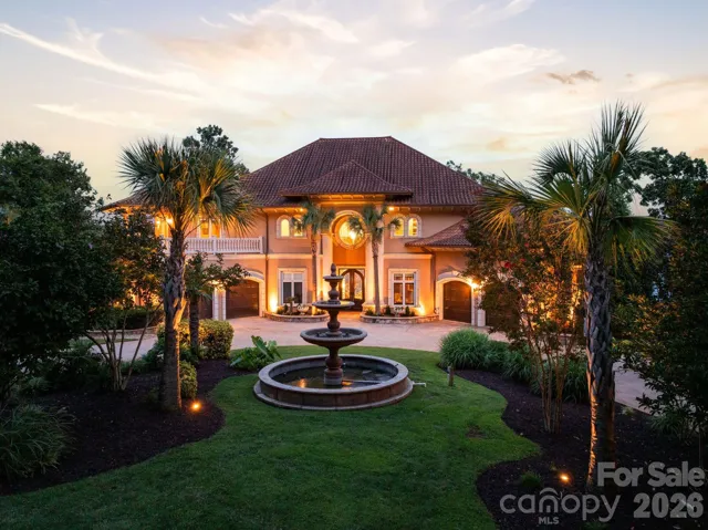 Impressive waterfront estate framed by mature landscaping, palm trees and an elegant circular fountain approach.