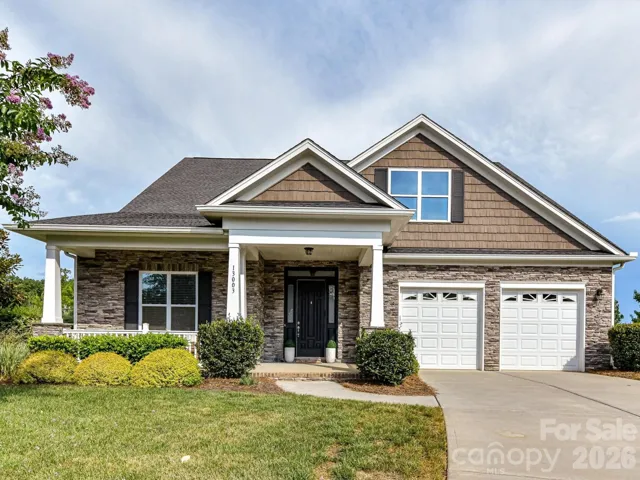 Beautifully maintained home with charming stone accents, a welcoming covered front porch, manicured landscaping and an attached two-car garage.