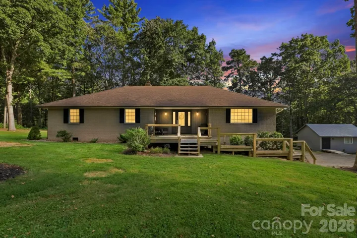 Welcoming brick home surrounded by mature trees and a beautifully maintained, park-like lawn.