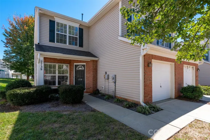 Move-in Ready 2-story townhome in Summerfield Townhomes featuring an attached 1-car garage, low-maintenance vinyl and partial brick exterior, concrete driveway, and neatly manicured landscaping.