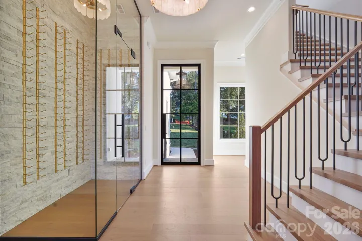 Grand foyer featuring a dramatic 10' steel front door and custom wine display, creating a striking first impression upon entry.