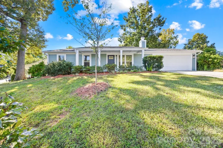 Front exterior of this one-level ranch home with fiber cement siding, attached two-car garage and mature trees
