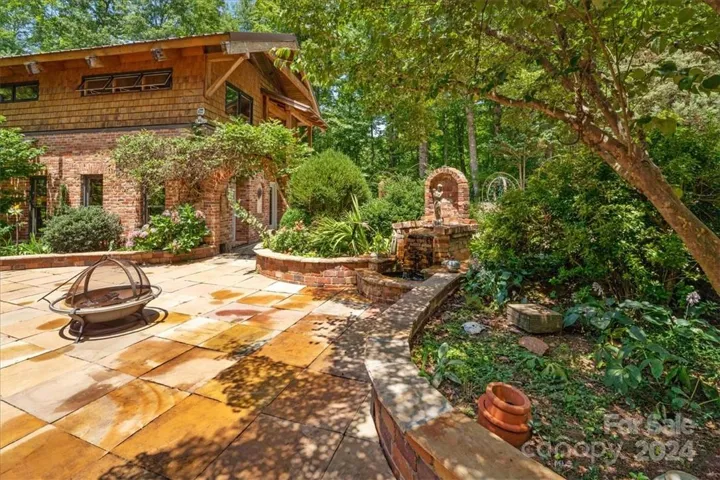 Side view of gorgeous unfinished brick and cedar shake building, with timber frame construction, that has opportunity for 2 additional living spaces. Gorgeous landscaping, custom brick and woodwork throughout!