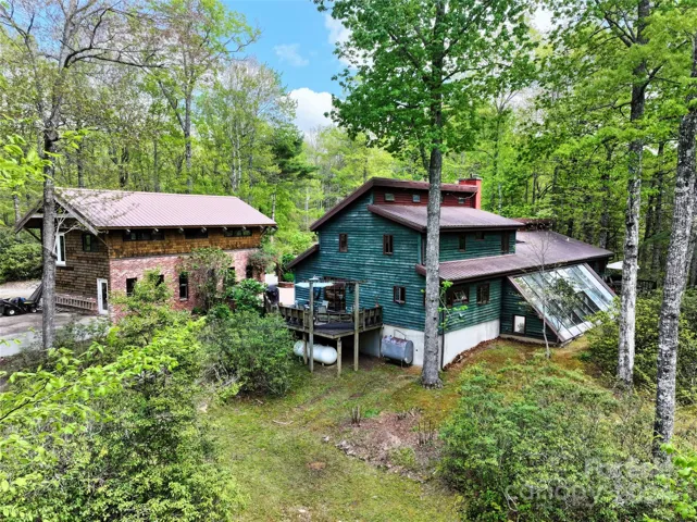 Back yard view of home with main house and unfinished home (brick and cedar shake exterior with opportunity for two additional living spaces.)