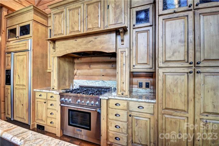 6 Burner Thermador gas range with hood, cabinet door refrigerator to the left