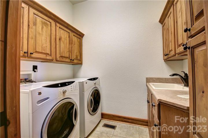 Lower-level laundry room with a sink and cabinets