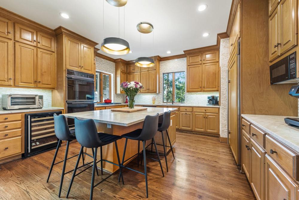 Updated kitchen with maple cabinets, microwave built into the large island, wine refrigerator, and gas cooktop.