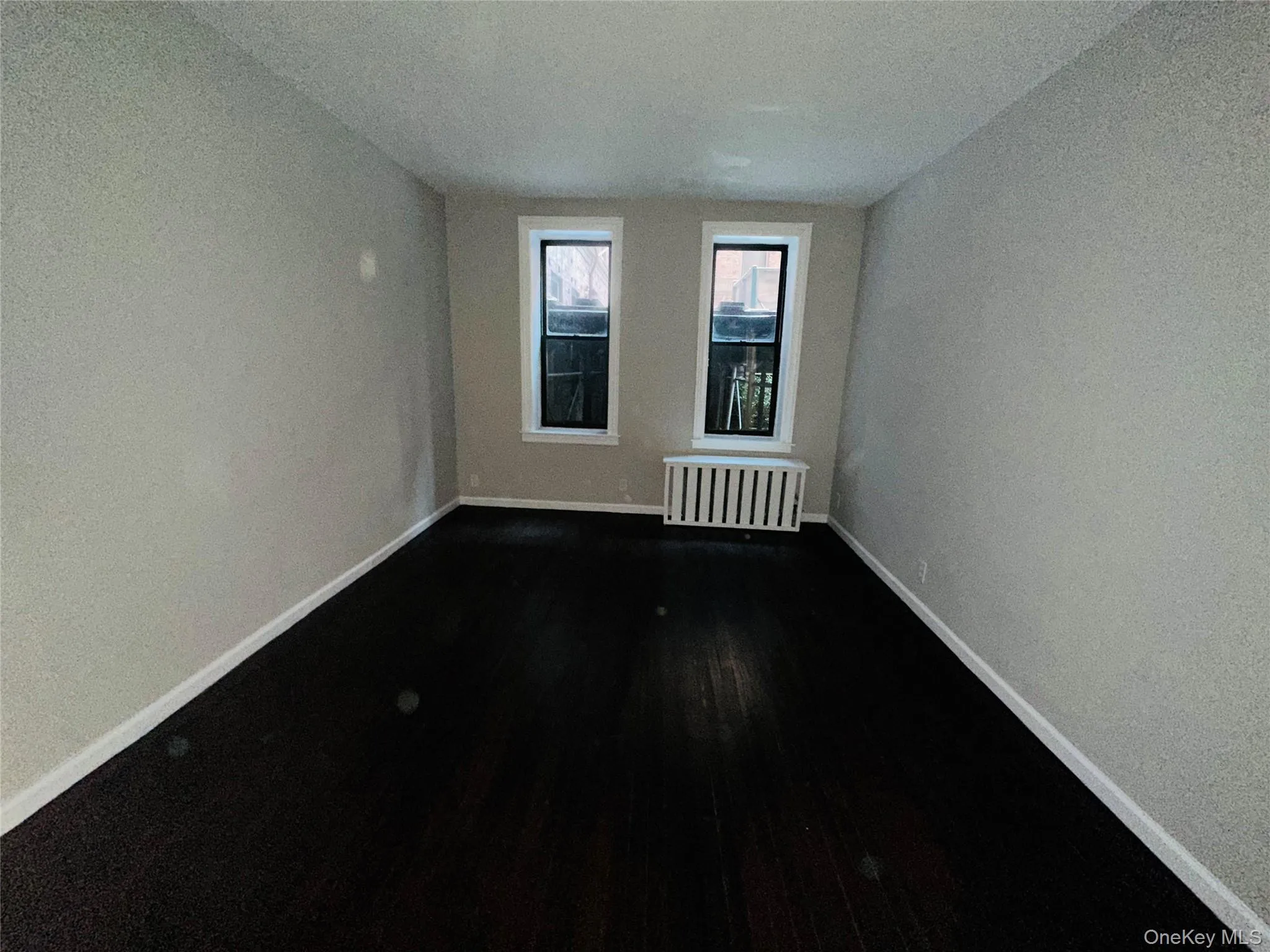 Unfurnished room with radiator, dark wood-type flooring, and a textured ceiling Unfurnished room with radiator, dark wood-type flooring, and a textured ceiling