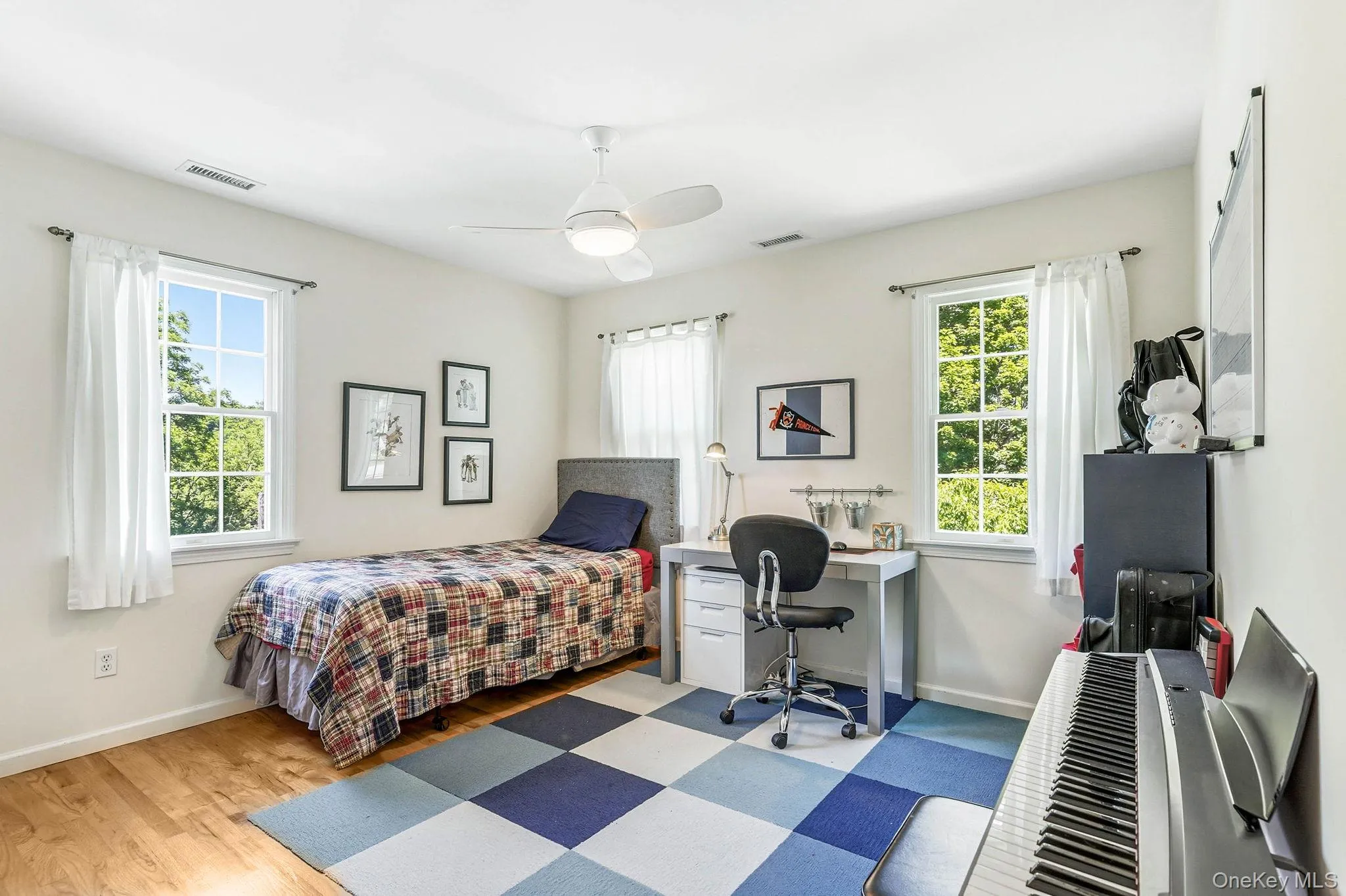 Light-filled room featuring wood-finish flooring, white walls, and a contemporary ceiling fan Light-filled room featuring wood-finish flooring, white walls, and a contemporary ceiling fan