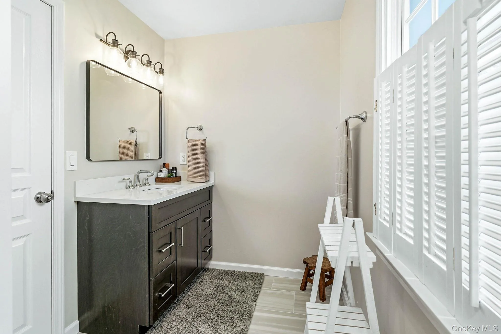 Bathroom featuring a dark wood-finish vanity with a white countertop, undermount sink, and a framed mirror Bathroom featuring a dark wood-finish vanity with a white countertop, undermount sink, and a framed mirror