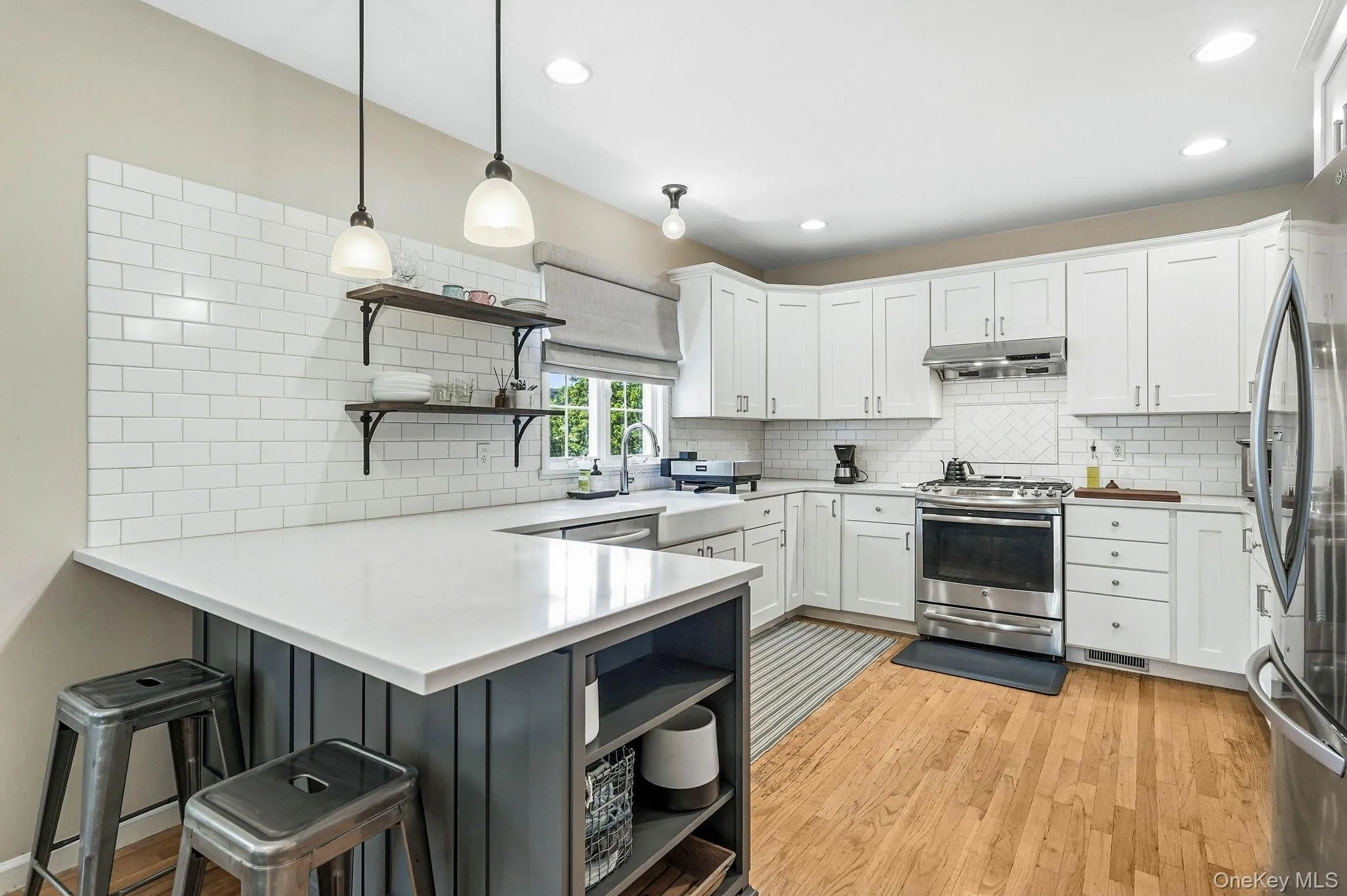 Bright kitchen featuring white shaker cabinetry, stainless steel appliances, and a farmhouse sink Bright kitchen featuring white shaker cabinetry, stainless steel appliances, and a farmhouse sink