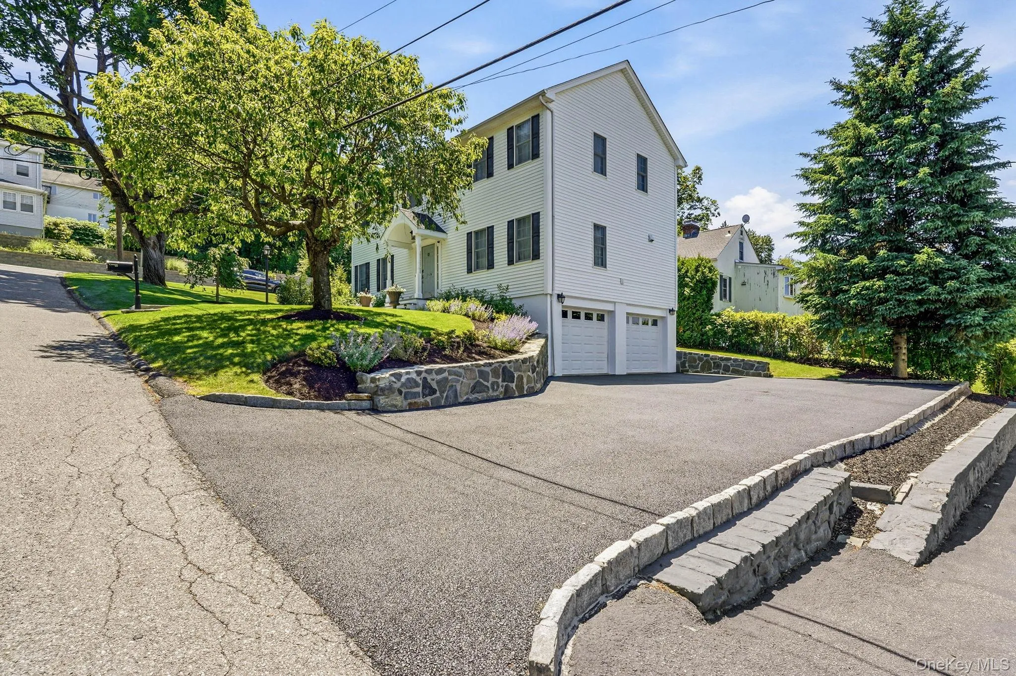 White siding residence featuring a two-car garage with white doors, black window shutters, and a covered front entry White siding residence featuring a two-car garage with white doors, black window shutters, and a covered front entry