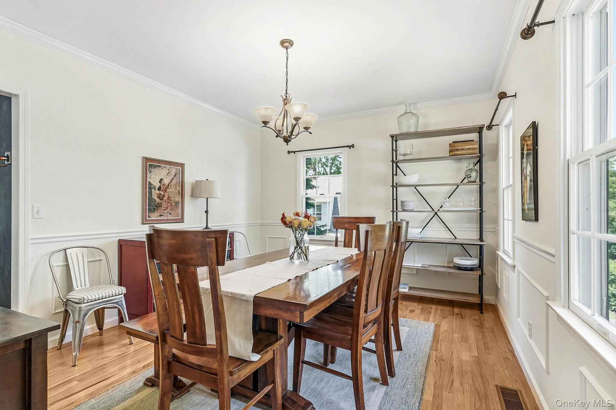 Formal dining area featuring hardwood flooring, crown molding, chair rail, and multiple windows Formal dining area featuring hardwood flooring, crown molding, chair rail, and multiple windows