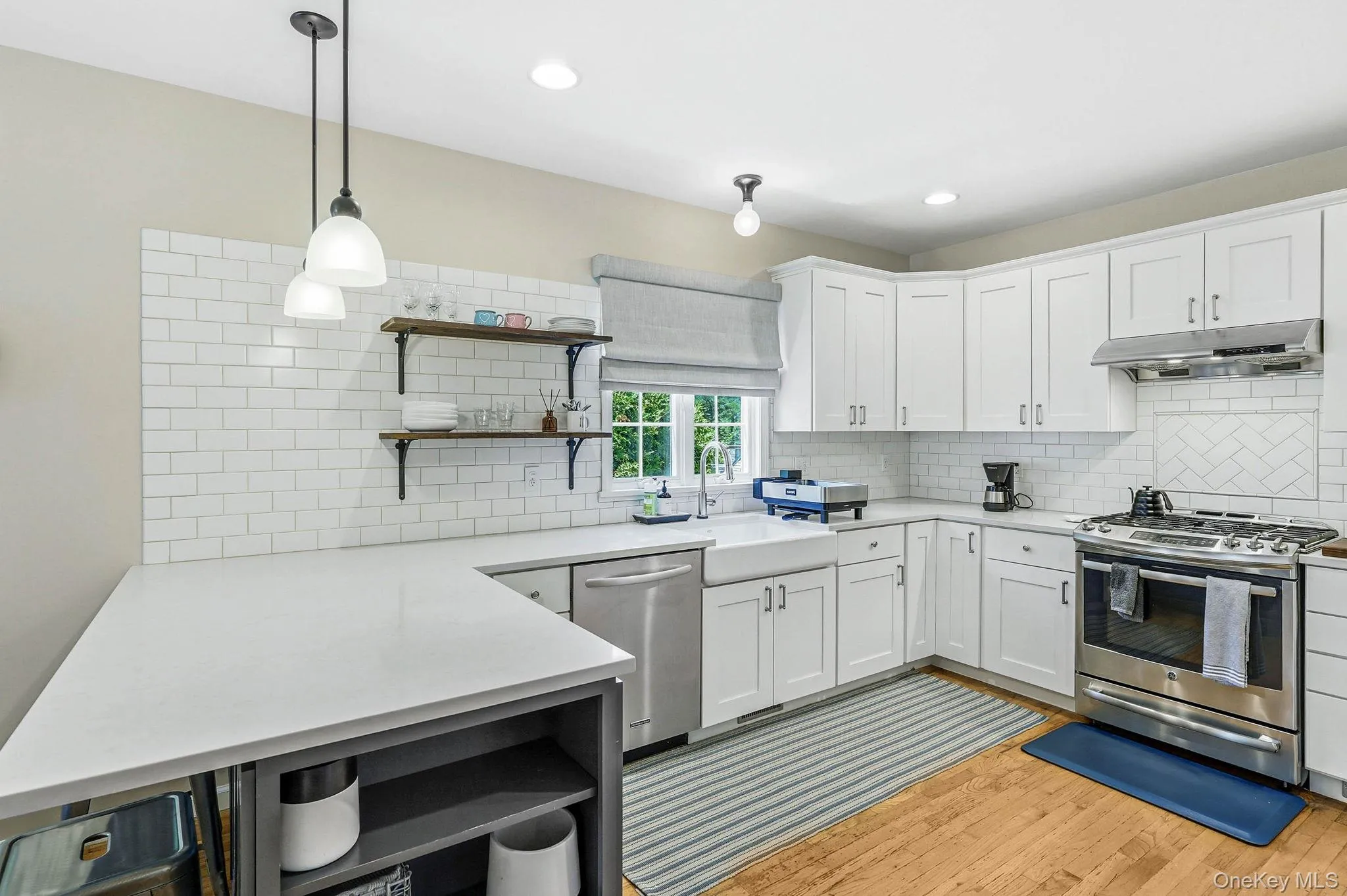 Kitchen featuring a farmhouse sink, stainless steel appliances, white cabinetry, and wood-finish flooring Kitchen featuring a farmhouse sink, stainless steel appliances, white cabinetry, and wood-finish flooring