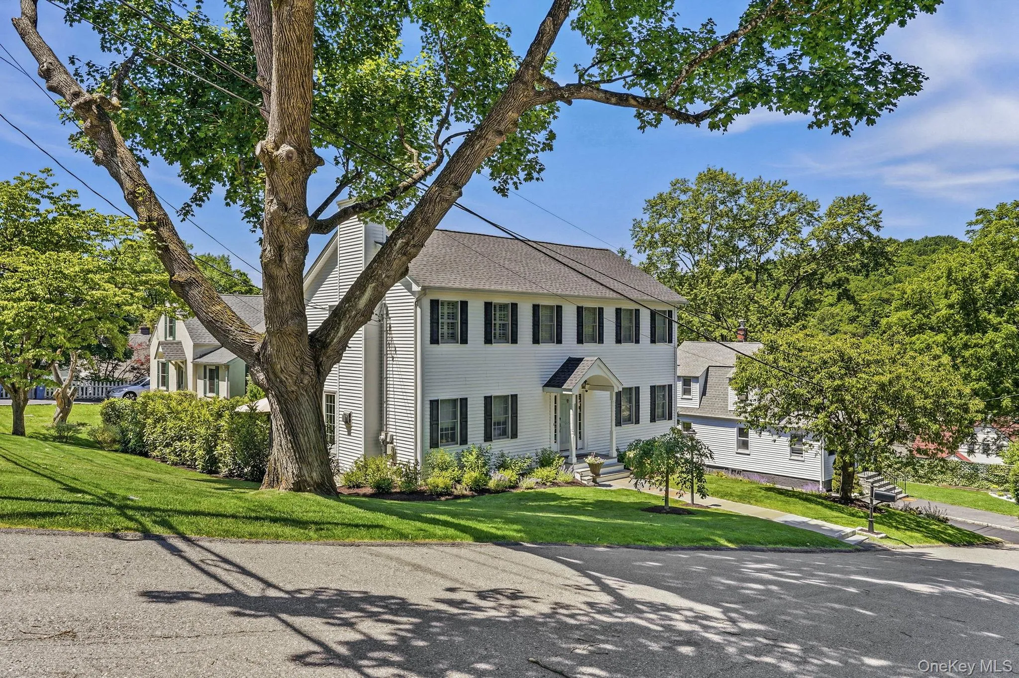 Two-story white residence featuring black window shutters, a covered entry, and a prominent chimney Two-story white residence featuring black window shutters, a covered entry, and a prominent chimney