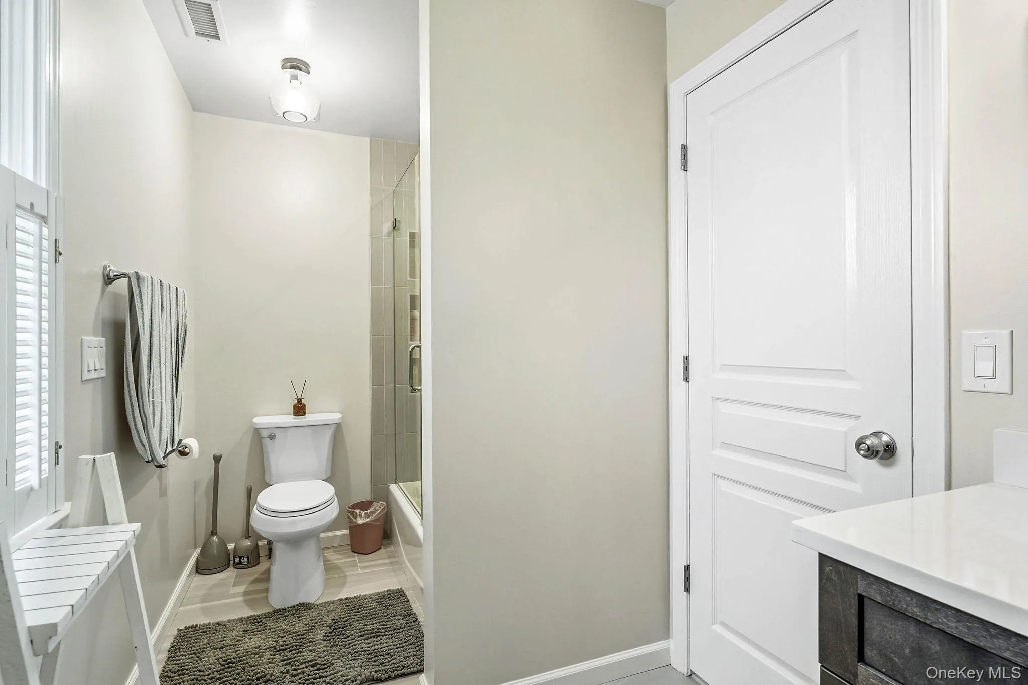 Bathroom featuring a glass-enclosed shower, white toilet, and neutral wall paint Bathroom featuring a glass-enclosed shower, white toilet, and neutral wall paint
