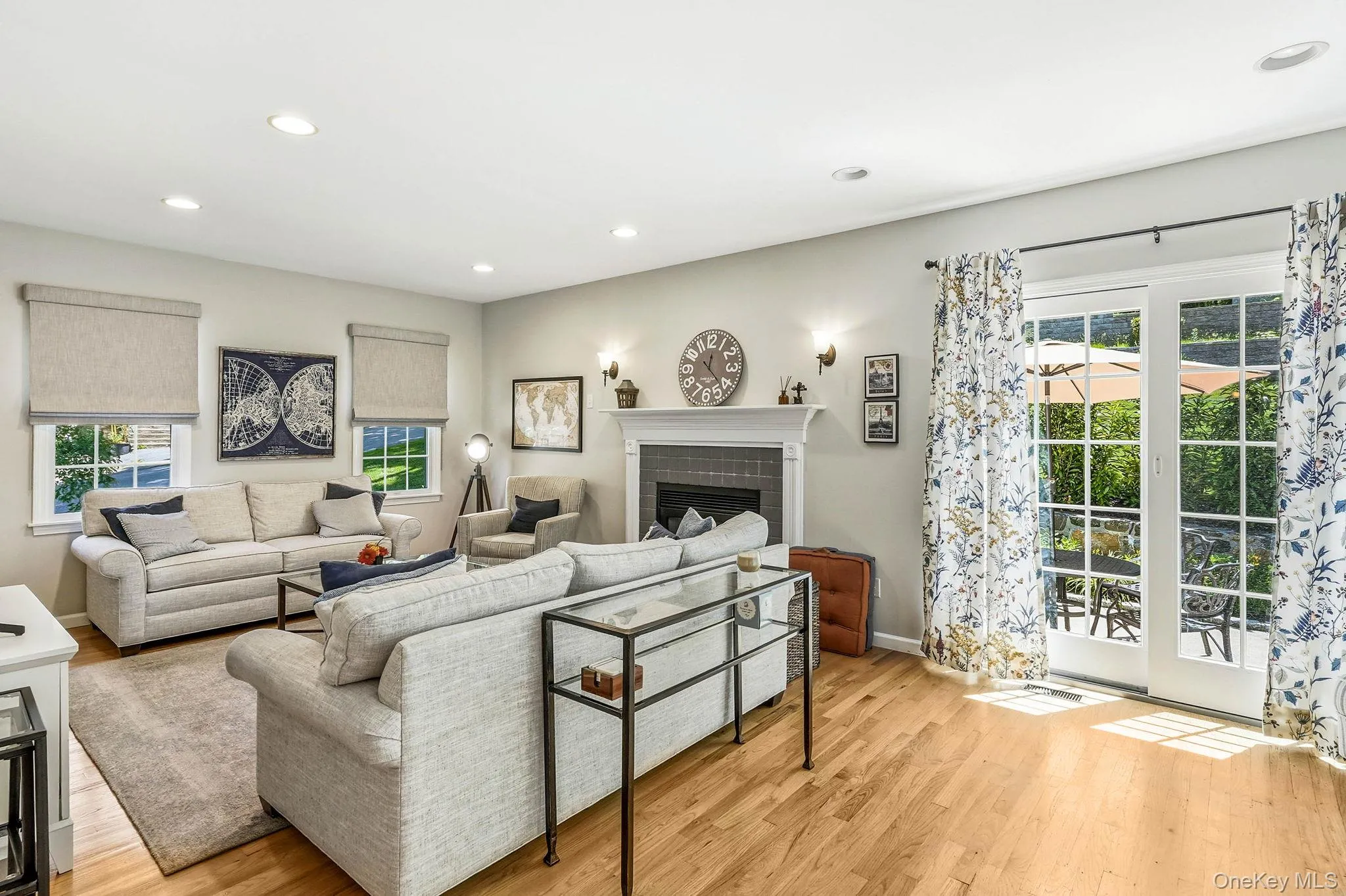 Spacious living area featuring wood-finish flooring, a fireplace with a mantel, and recessed lighting Spacious living area featuring wood-finish flooring, a fireplace with a mantel, and recessed lighting