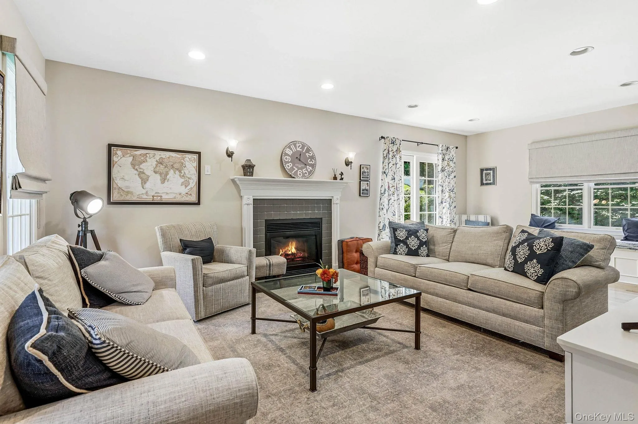 Living area featuring a fireplace with a white mantel and dark tile surround, recessed lighting, and light-toned walls Living area featuring a fireplace with a white mantel and dark tile surround, recessed lighting, and light-toned walls