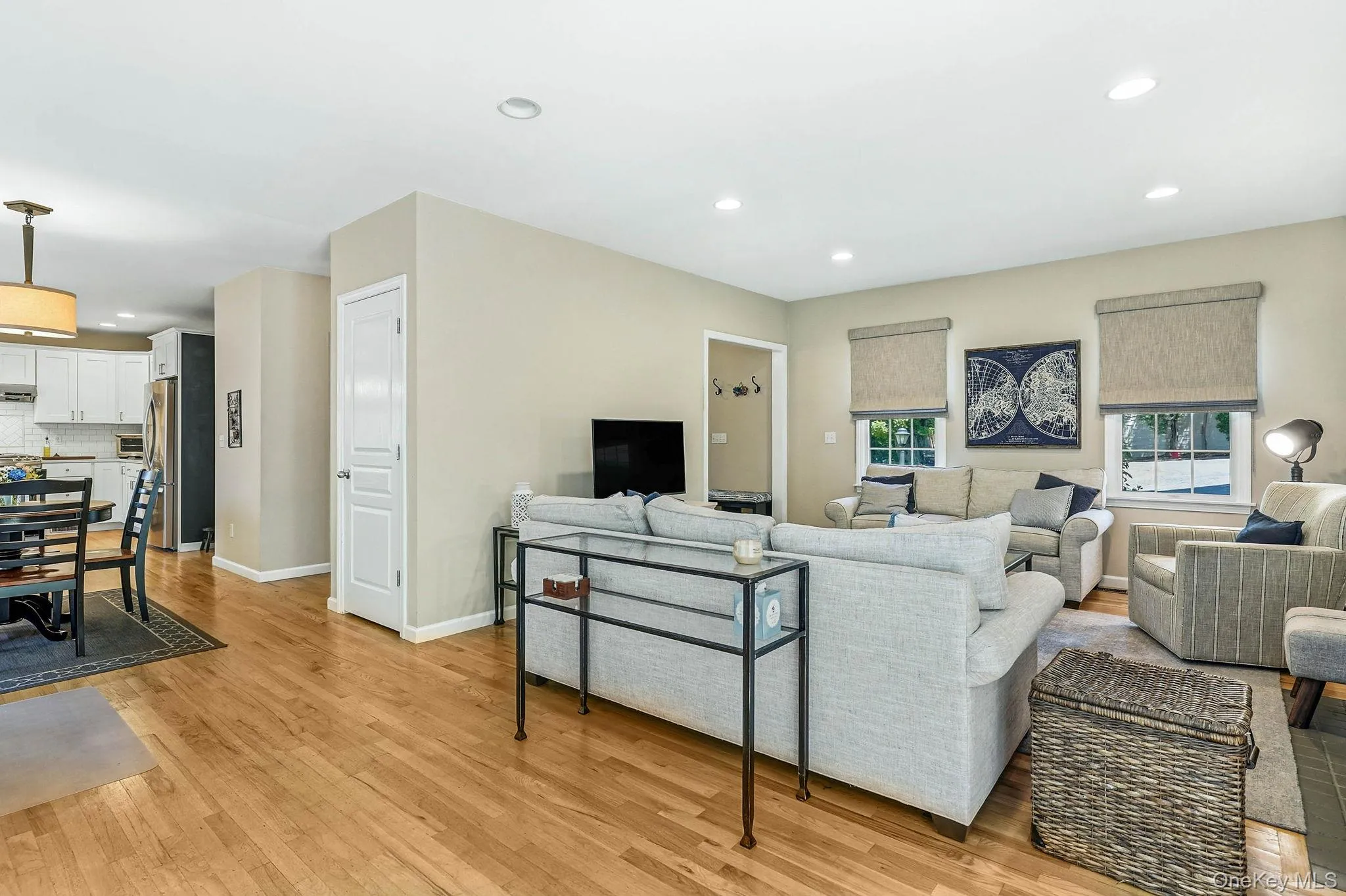 Open-concept living space featuring wood-finish flooring, recessed lighting, and neutral wall tones Open-concept living space featuring wood-finish flooring, recessed lighting, and neutral wall tones