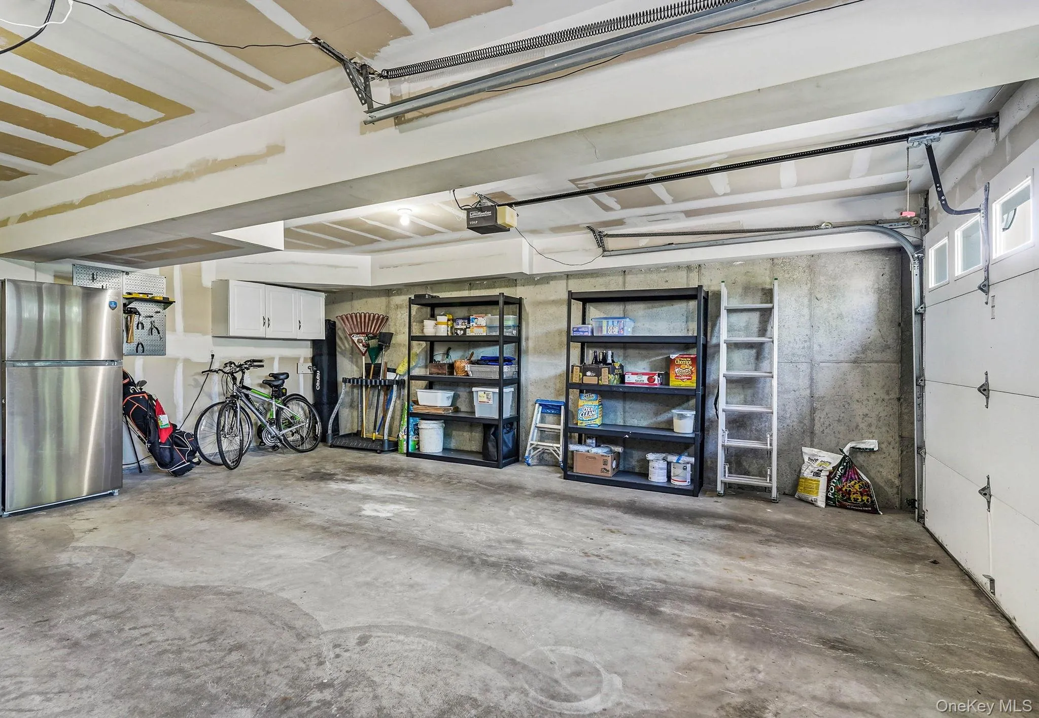 Spacious garage featuring a concrete floor, exposed ceiling beams, and concrete block walls Spacious garage featuring a concrete floor, exposed ceiling beams, and concrete block walls