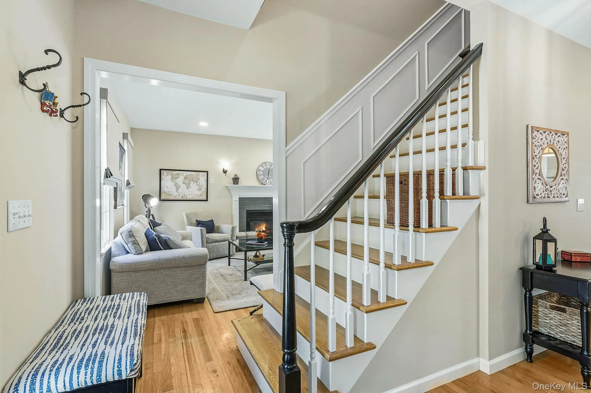 Hardwood flooring extending from the entryway into a living space featuring a fireplace with a mantel Hardwood flooring extending from the entryway into a living space featuring a fireplace with a mantel