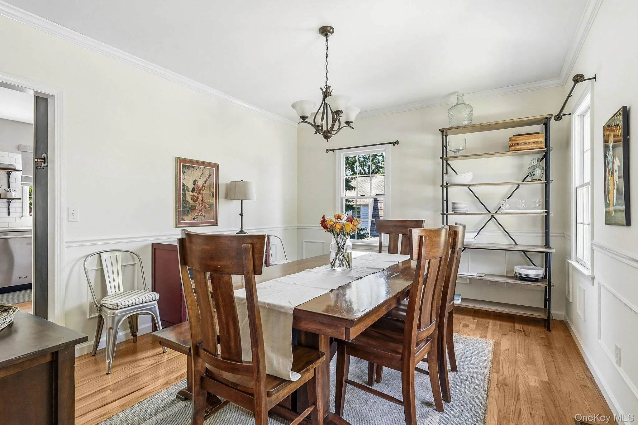 Dining area with hardwood flooring, wainscoting, crown molding, and an overhead chandelier Dining area with hardwood flooring, wainscoting, crown molding, and an overhead chandelier