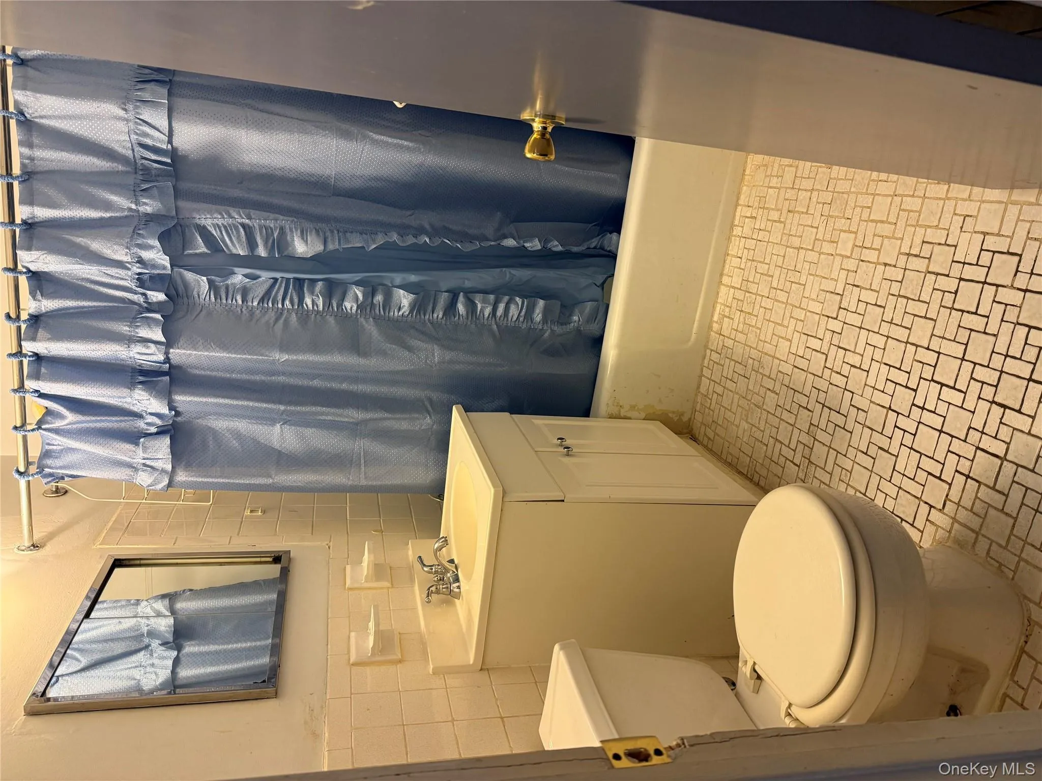Full bath with tile walls, shower / bath combo with shower curtain, vanity, and light tile patterned floors Full bath with tile walls, shower / bath combo with shower curtain, vanity, and light tile patterned floors