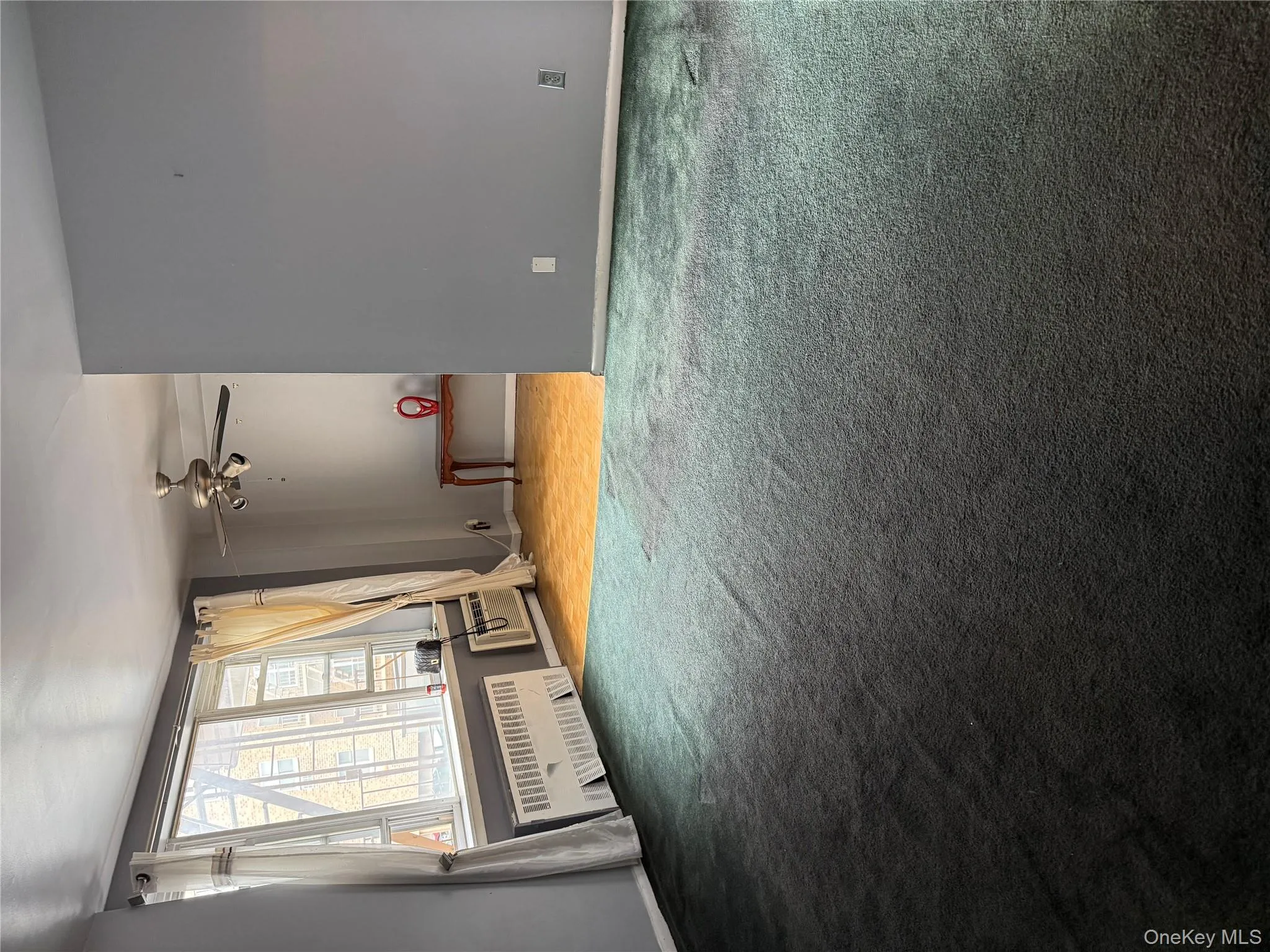 Unfurnished living room with radiator heating unit, light carpet, and ceiling fan Unfurnished living room with radiator heating unit, light carpet, and ceiling fan
