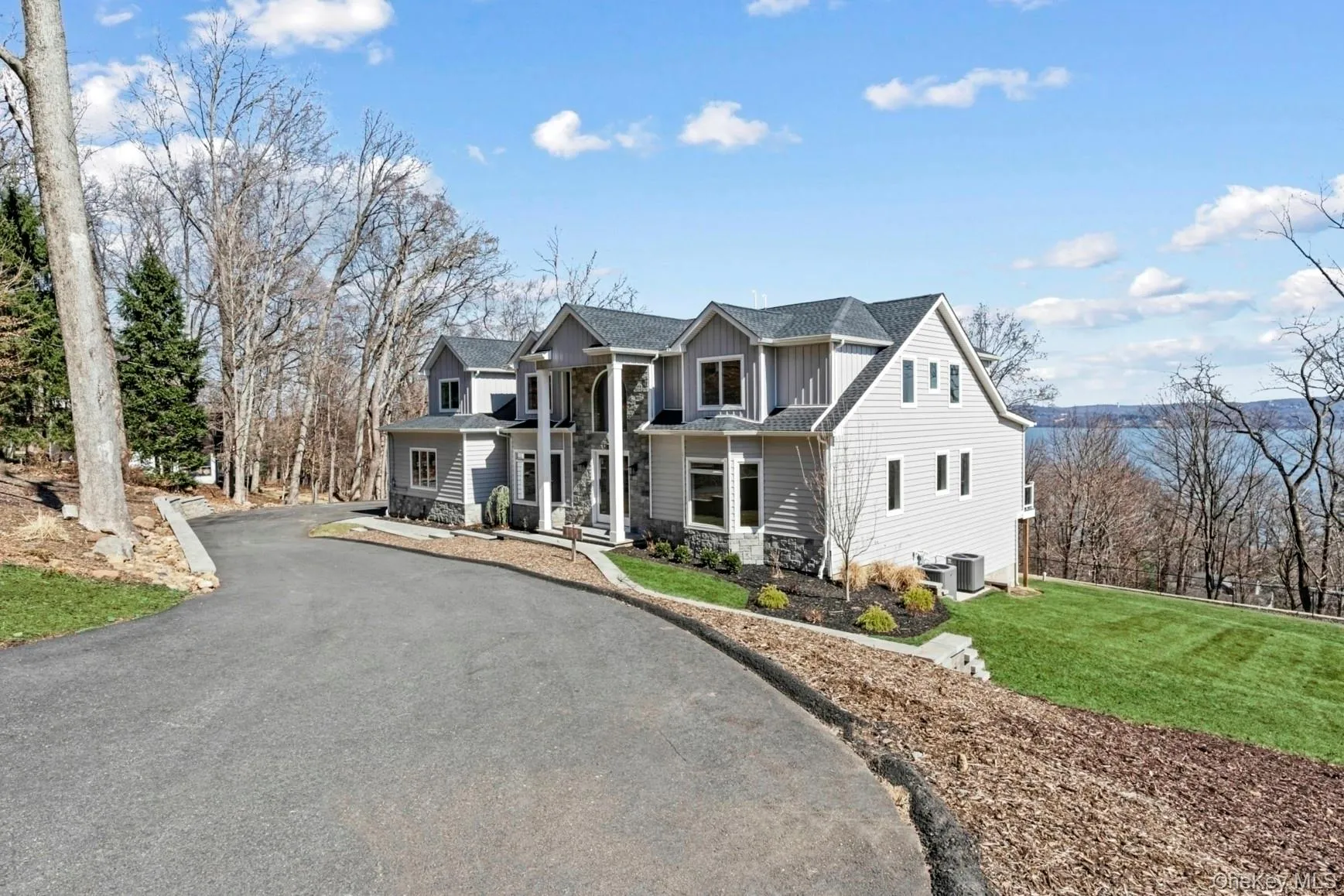 View of front of home with board and batten siding, driveway, stone siding, and a front lawn View of front of home with board and batten siding, driveway, stone siding, and a front lawn