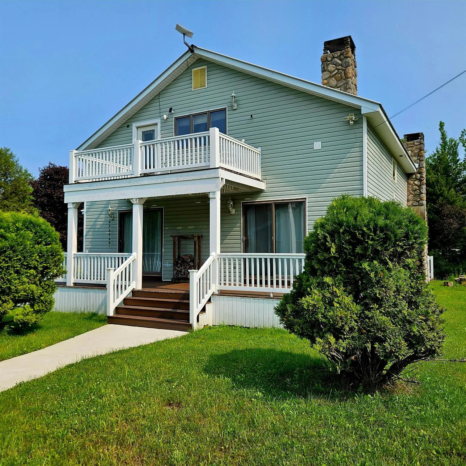 View of front facade with a balcony, a chimney, a porch, and a front yard View of front facade with a balcony, a chimney, a porch, and a front yard