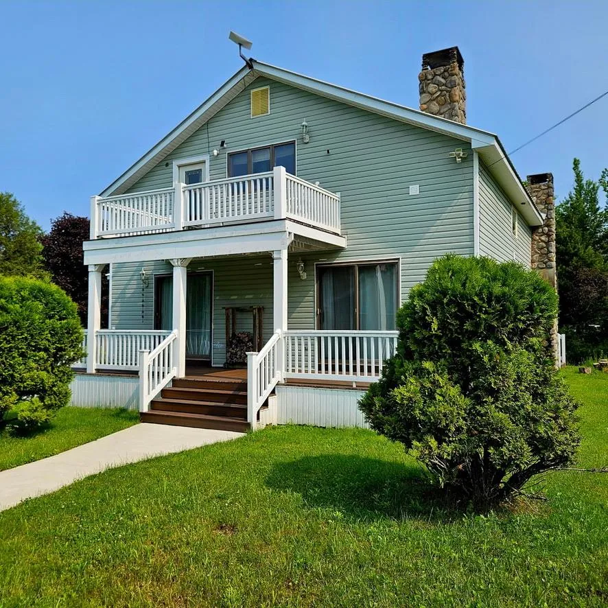 View of front facade with a balcony, a porch, a chimney, and a front yard View of front facade with a balcony, a porch, a chimney, and a front yard