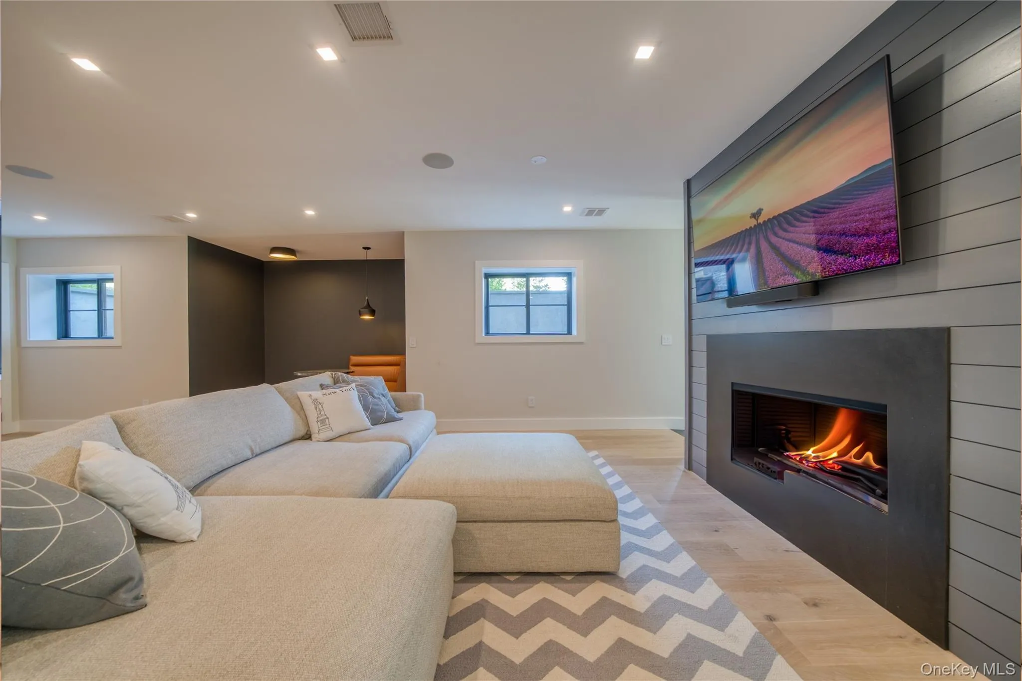 Media/lounge room with a large fireplace, a healthy amount of sunlight, and light hardwood / wood-style flooring Media/lounge room with a large fireplace, a healthy amount of sunlight, and light hardwood / wood-style flooring