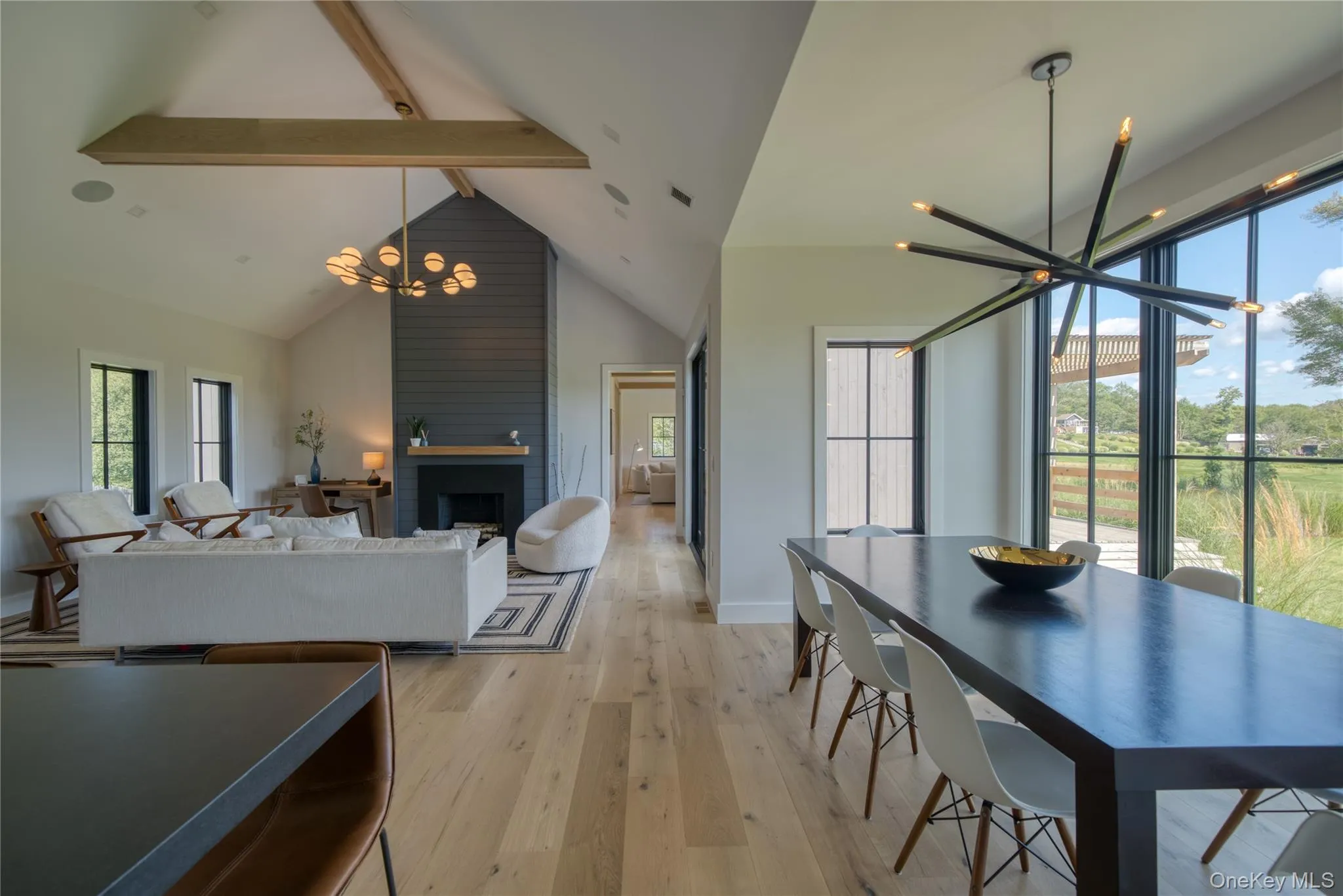 Dining area with light hardwood / wood-style floors, beamed ceiling, plenty of natural light, a large fireplace, and a chandelier Dining area with light hardwood / wood-style floors, beamed ceiling, plenty of natural light, a large fireplace, and a chandelier