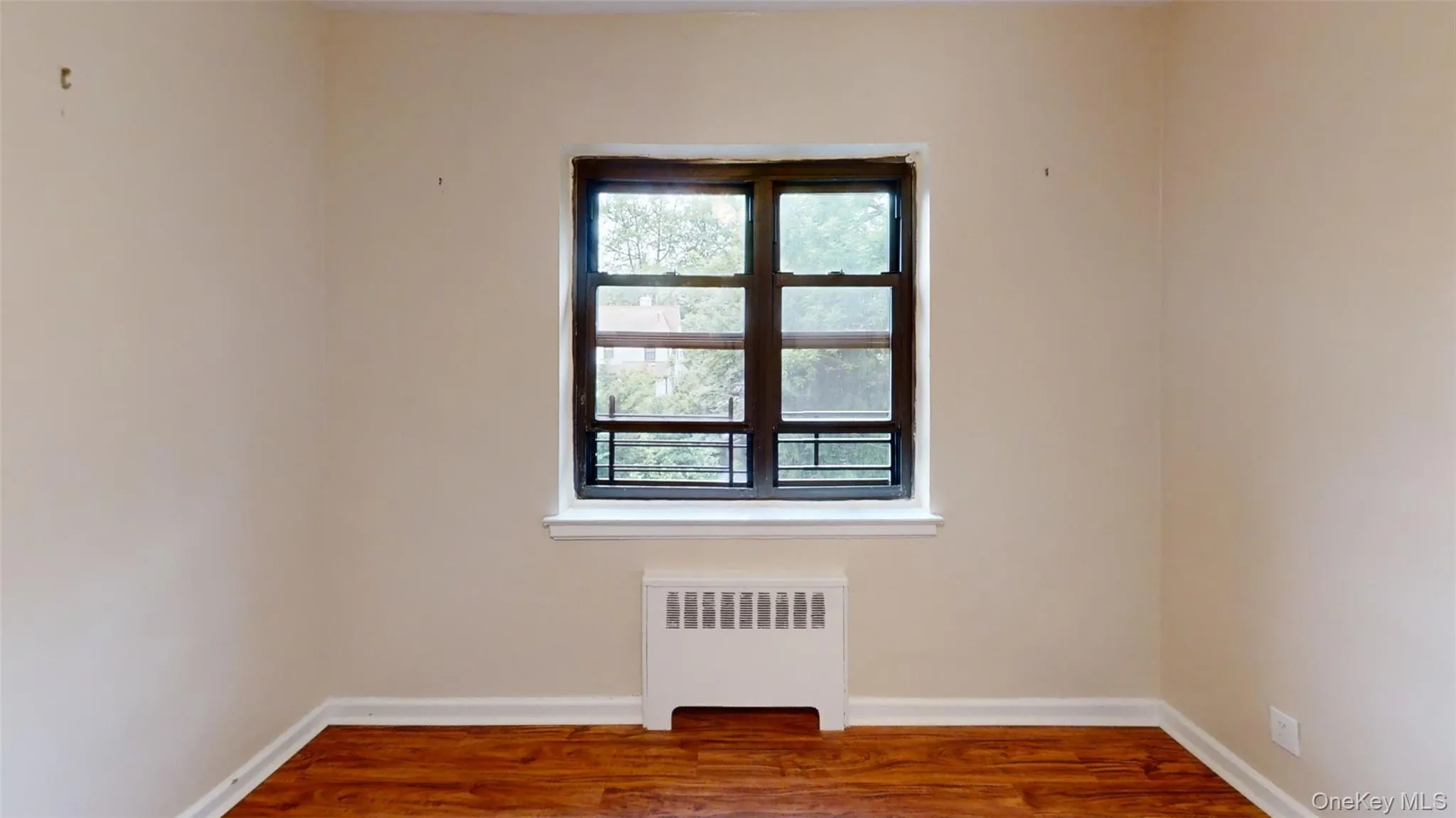 Unfurnished room featuring radiator, baseboards, and wood finished floors Unfurnished room featuring radiator, baseboards, and wood finished floors