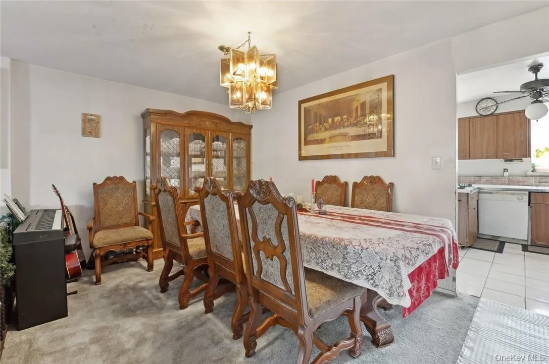 Dining space featuring light colored carpet and ceiling fan with notable chandelier Dining space featuring light colored carpet and ceiling fan with notable chandelier