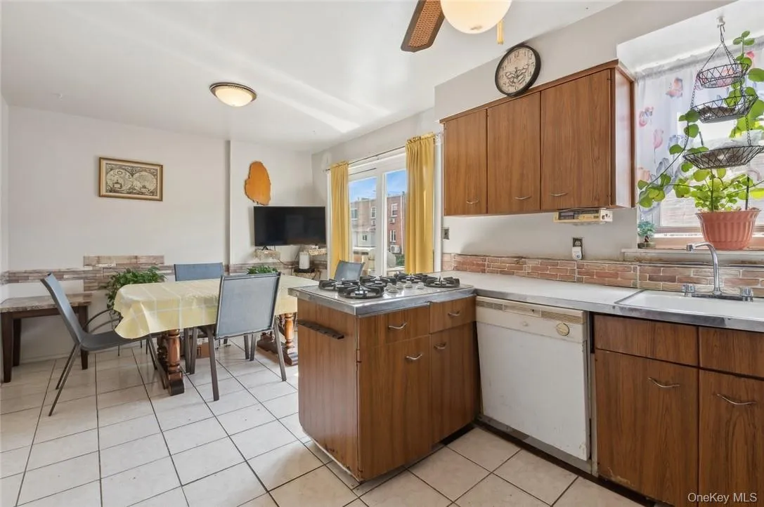 Kitchen with ceiling fan, dishwasher, stainless steel gas stovetop, light tile flooring, and sink Kitchen with ceiling fan, dishwasher, stainless steel gas stovetop, light tile flooring, and sink