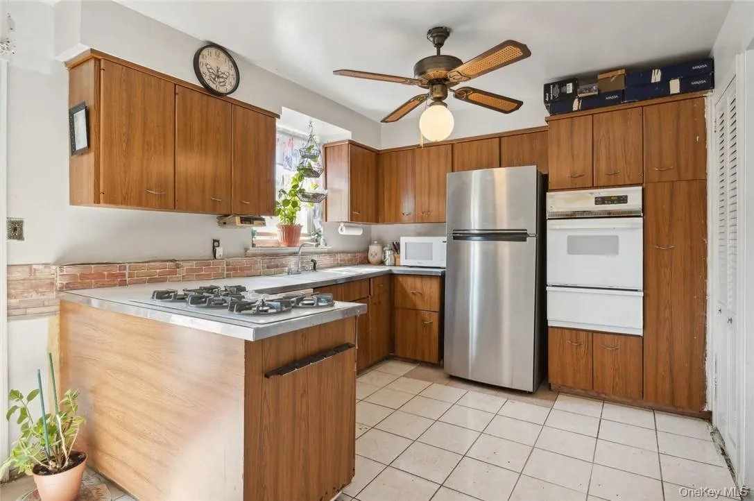 Kitchen featuring white appliances, sink, ceiling fan, and light tile floors Kitchen featuring white appliances, sink, ceiling fan, and light tile floors
