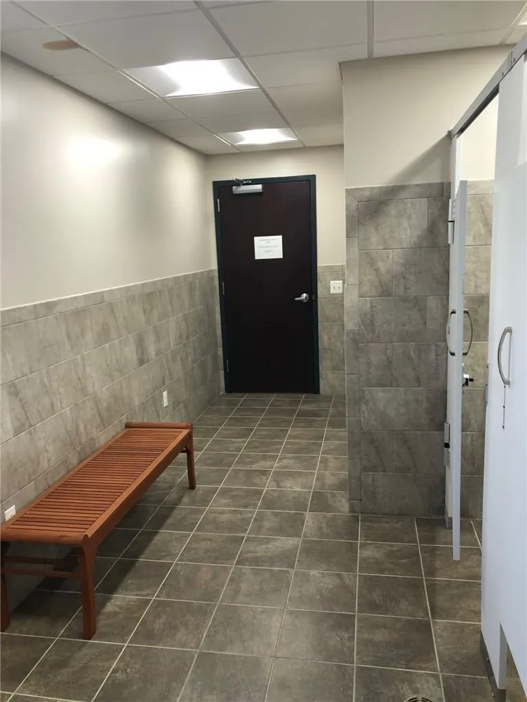 Hallway with dark tile floors, tile walls, and a drop ceiling Hallway with dark tile floors, tile walls, and a drop ceiling