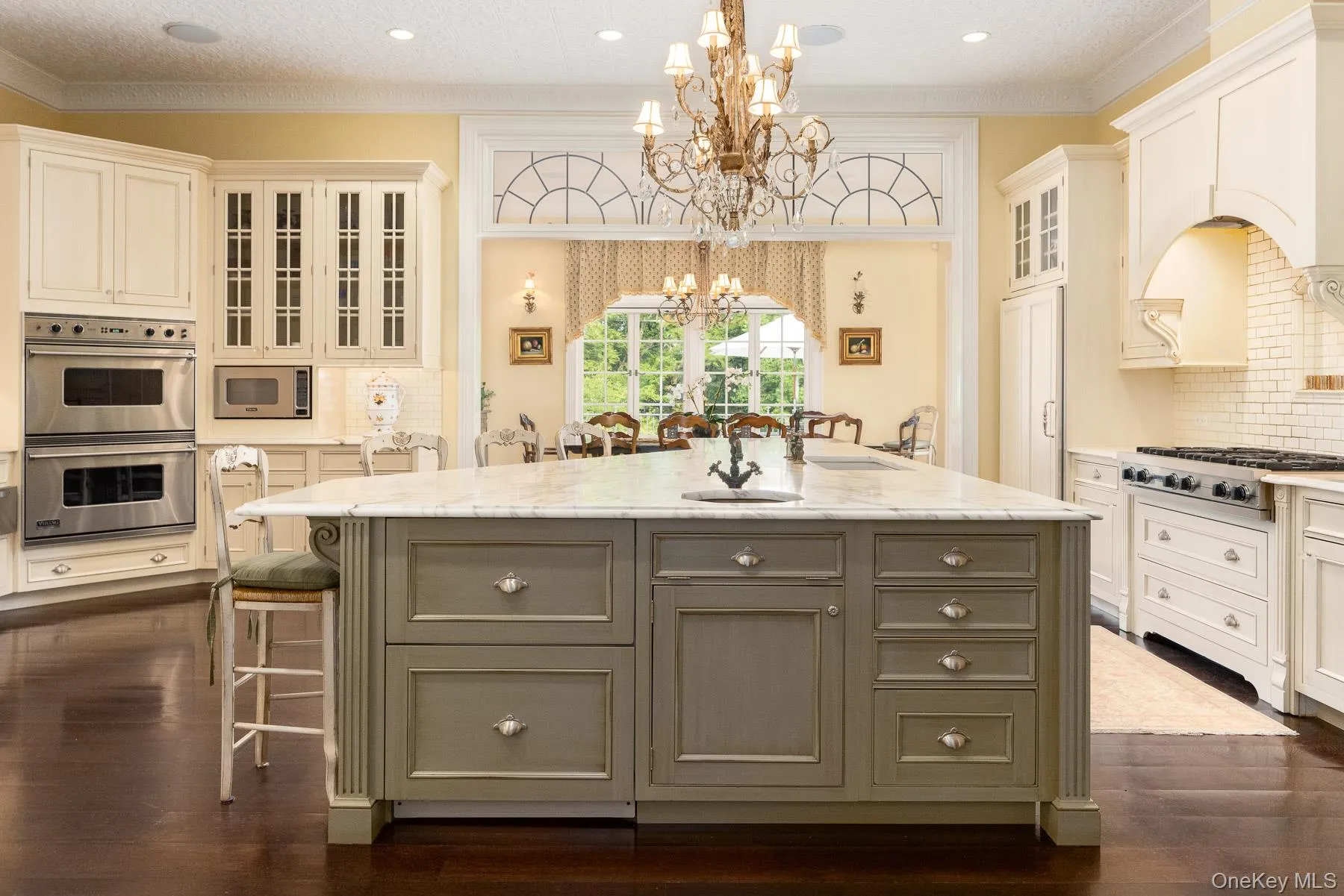 Kitchen with tasteful backsplash, glass insert cabinets, ornamental molding, pendant lighting, and a kitchen bar Kitchen with tasteful backsplash, glass insert cabinets, ornamental molding, pendant lighting, and a kitchen bar