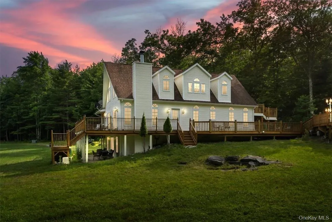 Back house at dusk with a wooden deck and a lawn Back house at dusk with a wooden deck and a lawn