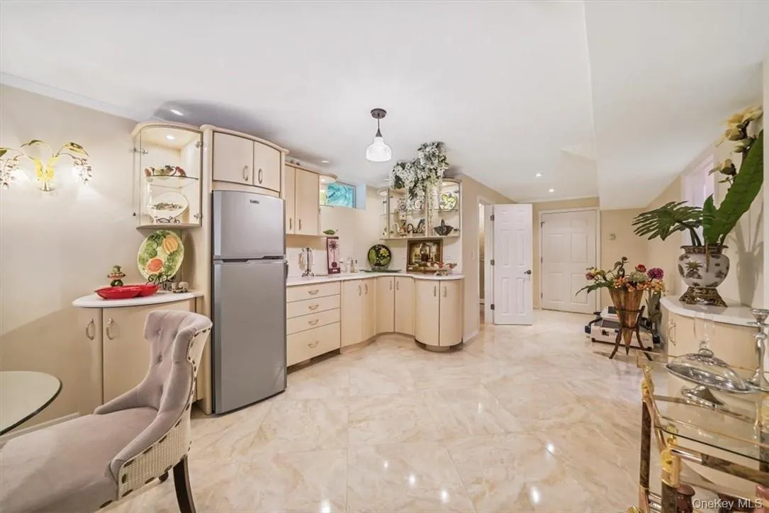 Kitchen with decorative light fixtures, stainless steel refrigerator, cream cabinetry, and light tile patterned flooring Kitchen with decorative light fixtures, stainless steel refrigerator, cream cabinetry, and light tile patterned flooring