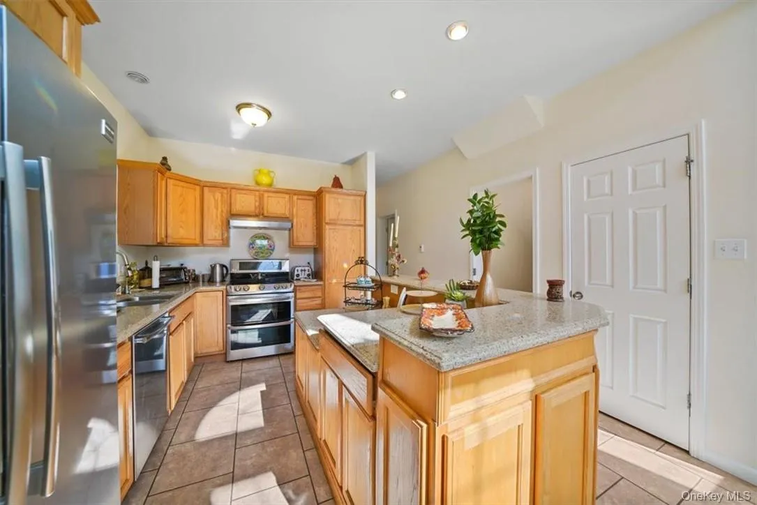 Kitchen with appliances with stainless steel finishes, light tile patterned floors, sink, and a kitchen island Kitchen with appliances with stainless steel finishes, light tile patterned floors, sink, and a kitchen island