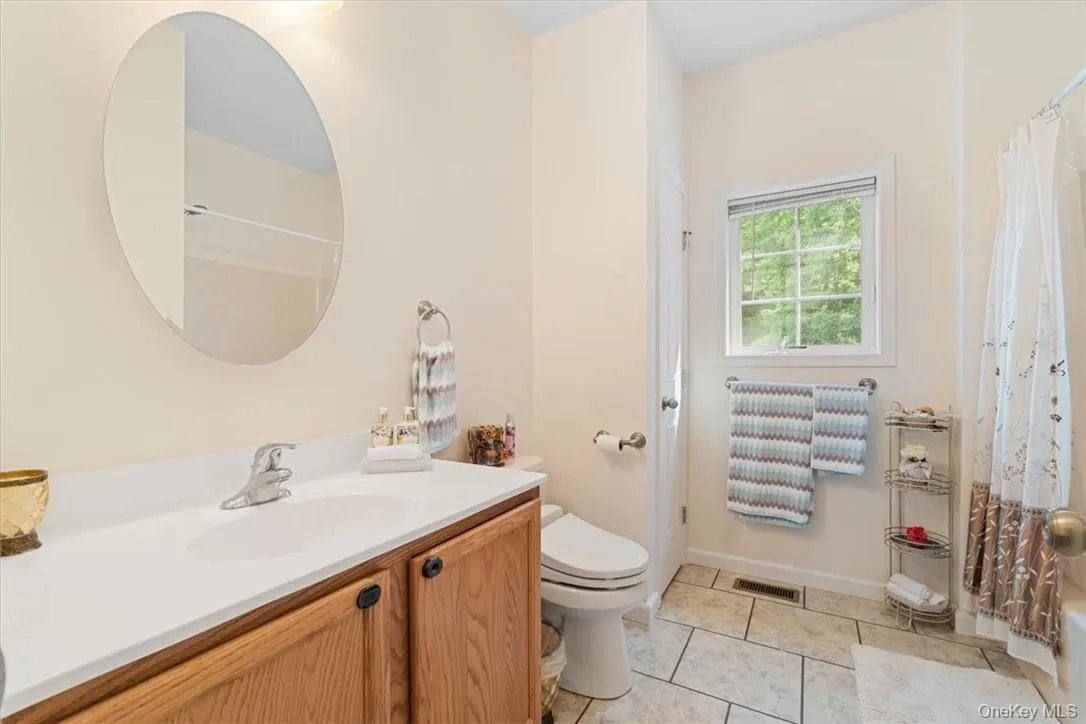 Bathroom featuring vanity, toilet, and tile patterned flooring Bathroom featuring vanity, toilet, and tile patterned flooring
