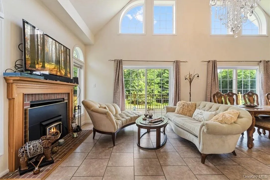 Tiled living room with a brick fireplace, high vaulted ceiling, and an inviting chandelier Tiled living room with a brick fireplace, high vaulted ceiling, and an inviting chandelier