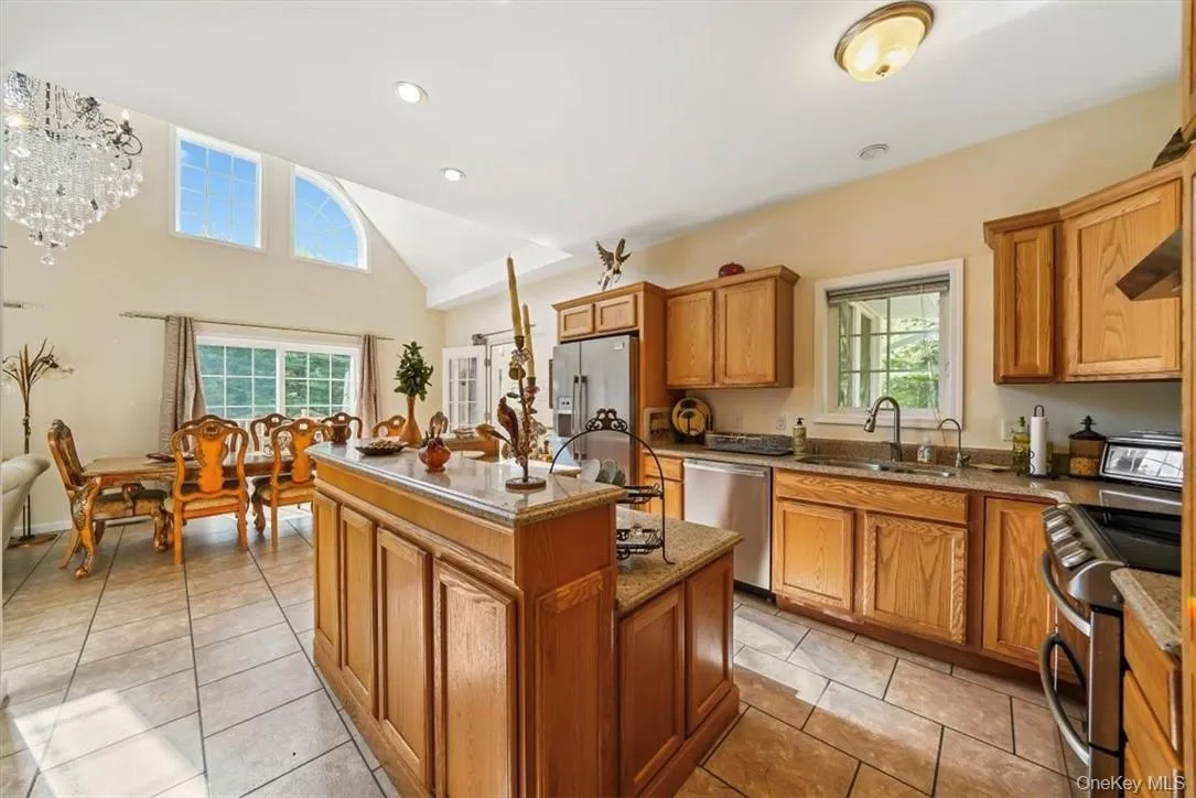 Kitchen featuring appliances with stainless steel finishes, a healthy amount of sunlight, light tile patterned floors, and a kitchen island Kitchen featuring appliances with stainless steel finishes, a healthy amount of sunlight, light tile patterned floors, and a kitchen island