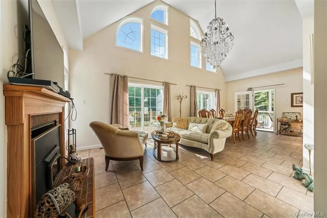 Tiled living room with an inviting chandelier, a healthy amount of sunlight, and high vaulted ceiling Tiled living room with an inviting chandelier, a healthy amount of sunlight, and high vaulted ceiling