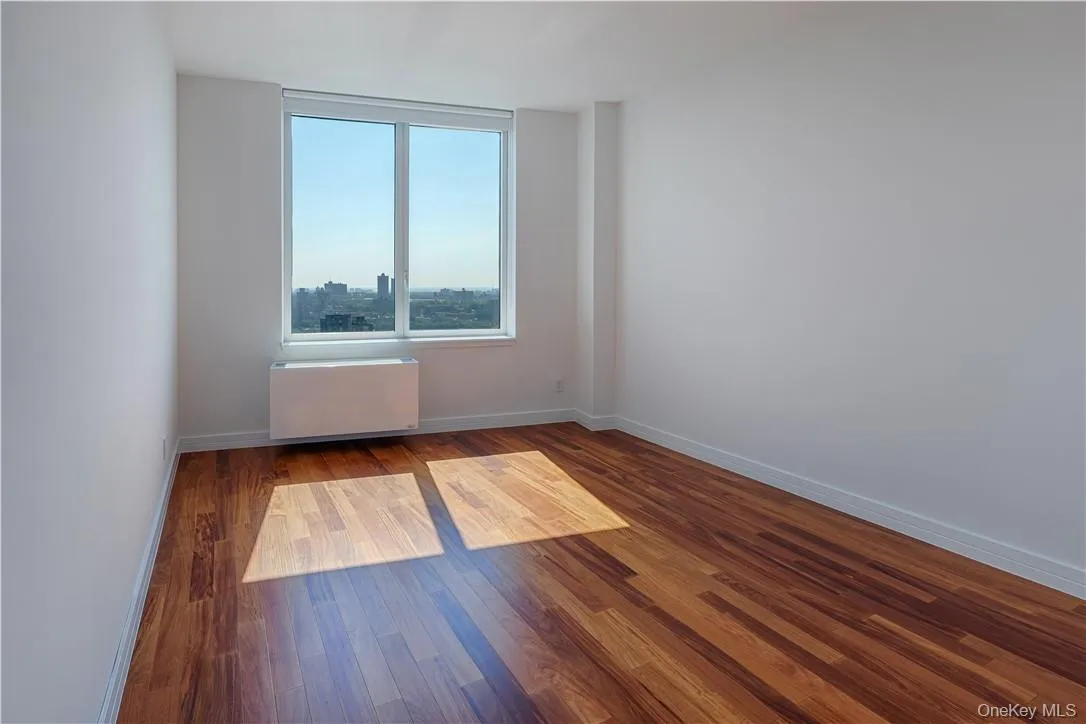 Empty room featuring radiator and hardwood / wood-style flooring Empty room featuring radiator and hardwood / wood-style flooring