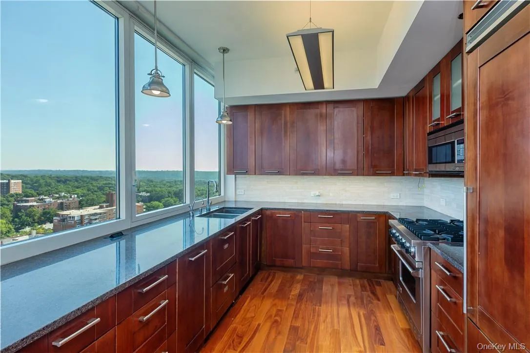 Kitchen featuring hardwood / wood-style flooring, decorative light fixtures, backsplash, and built in appliances Kitchen featuring hardwood / wood-style flooring, decorative light fixtures, backsplash, and built in appliances